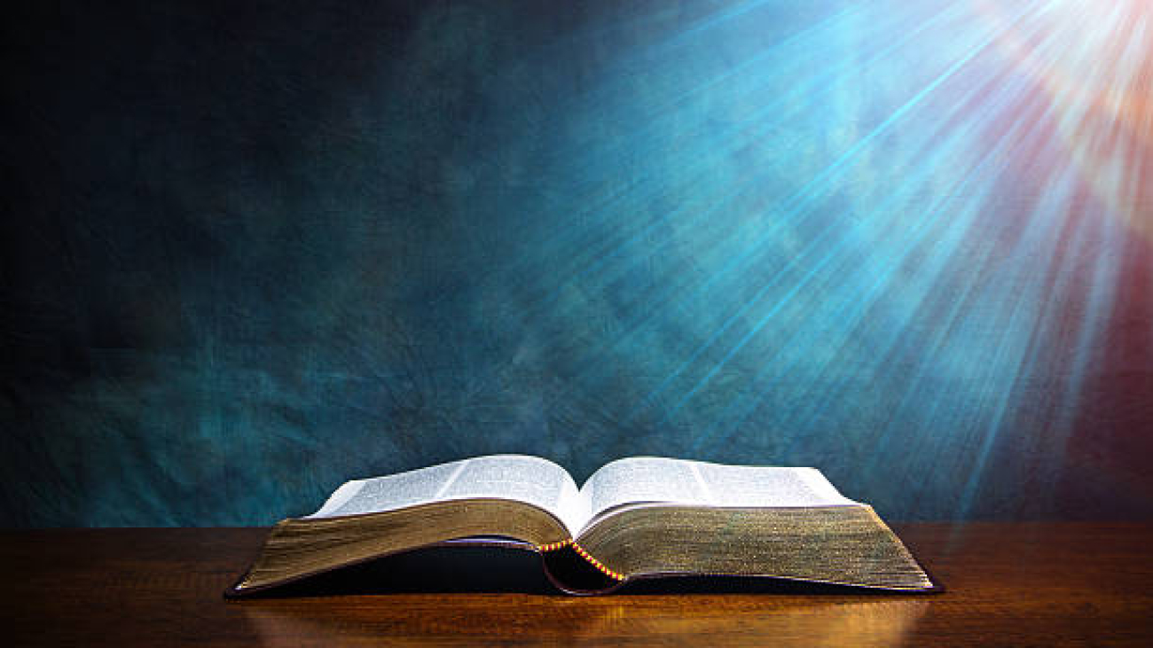Open Bible on a wood table with light coming from above. ( church concept ).