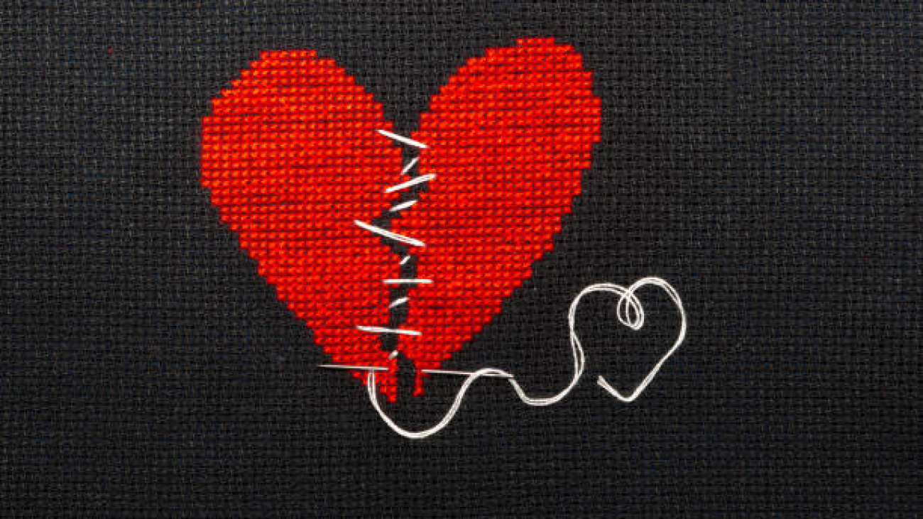 Two halves heart embroidered red thread on black fabric. Two halves heart sewn with black thread.